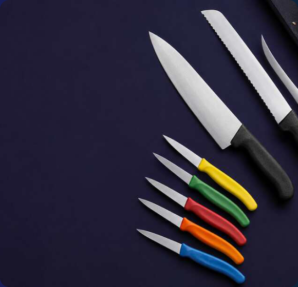 Victorinox chef’s and serrated knives with black Fibrox handles plus colour-coded Swiss Classic paring knives on a dark navy background